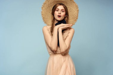 Mavi arka planda pembe elbiseli bir kız elleriyle romantik modeller yapıyor.