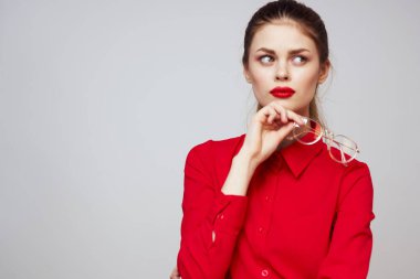 Kırmızı gömlekli şık bir kadın açık arkaplanda eğlenceli duygular parlak makyaj gözlükleri çekici bir görünüş. 