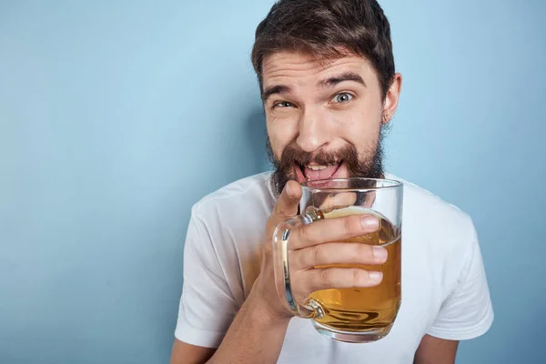 Hombre alegre en una camiseta blanca con una taza de cerveza borracho fondo azul —  Fotos de Stock