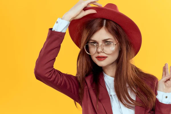 Mujer en rojo sombrero chaqueta gafas amarillo fondo cosméticos — Foto de Stock