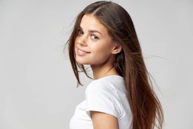 Gevşek saçlı bir kadın gülümser ve ileriye bakar. 