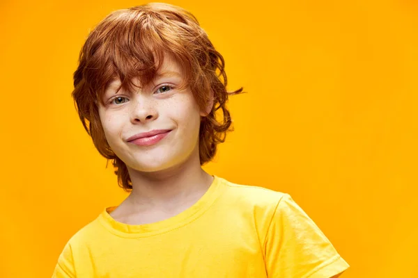 Rudowłosy chłopiec w żółtej koszulce na odosobnionym tle — Zdjęcie stockowe