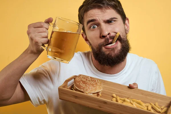 Homme barbu avec tasse de bière fast food régime alimentaire plaisir alcool style de vie fond jaune — Photo