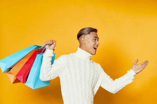 Chico feliz con bolsas de compras y fondo amarillo — Foto de Stock