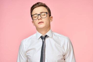 Beyaz gömlekli, kravatlı, gözlüklü, kendine güvenen, resmi pembe arka planlı bir iş adamı.
