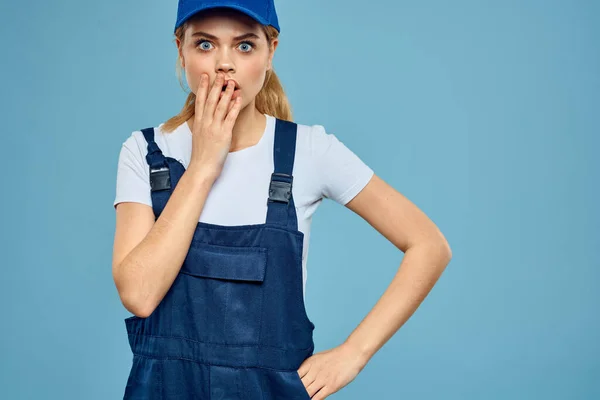 Kvinna i arbete uniform blå mössa vagn leverans kurir blå bakgrund — Stockfoto