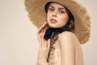 Hasır şapkalı, siyah kurdeleli ve arka planda açık bir elbise giyen hoş bir kız. Romantik bir model.