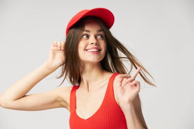 Gülümseyen kadın yana bakar ve parmağıyla kırmızı bir şapka gösterir. 