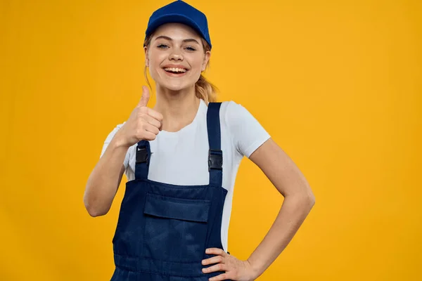 Mulher em uniforme de trabalho tampa azul entregando serviço de correio fundo amarelo — Fotografia de Stock