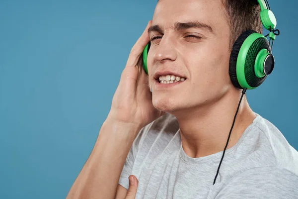 Hombre con auriculares verdes escucha música entretenimiento estilo de vida blanco camiseta fondo azul — Foto de Stock