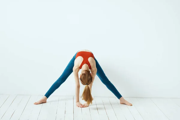 Sportovní žena póza gymnastika rovnováha cvičení lehké pozadí — Stock fotografie