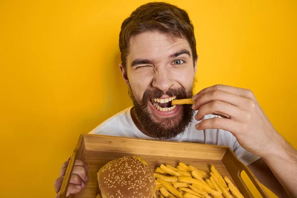 Mężczyzna z drewnianą paletą fast food hamburger frytki dieta spożywcza zbliżenie — Zdjęcie stockowe