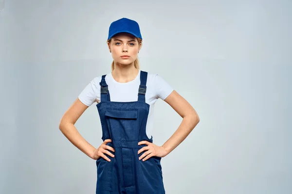 Kvinna i arbete uniform blå mössa tjänst leverans service ljus bakgrund — Stockfoto