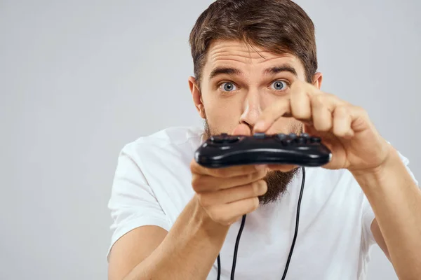 Un hombre con un joystick en sus manos diversión juegos estilo de vida blanco camiseta fondo claro —  Fotos de Stock