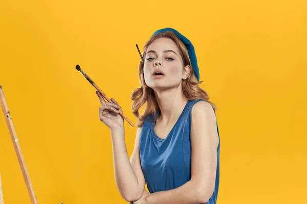 Künstler Frau in blauer Baskenmütze Pinsel Staffelei Kunst Zeichnung Bildung Hobby Kreativer Ansatz gelber Hintergrund — Stockfoto