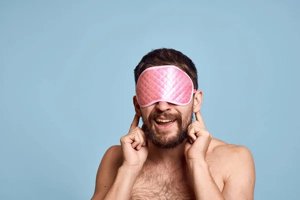 Homem barbudo emocional em uma máscara para dormir fundo azul close-up — Fotografia de Stock