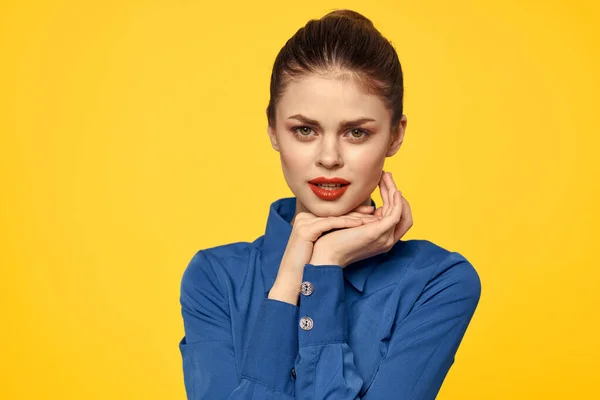 파란색 셔츠를 입고 노란 배경 감정에 붉은 입술을 하고 있는 엄격 한 여자의 사진 — 스톡 사진