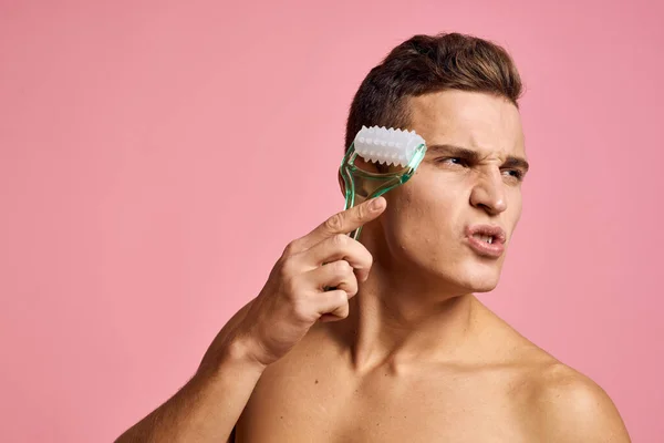 Homem bonito com massageador na mão sobre fundo rosa isolado corte vista pele limpa — Fotografia de Stock