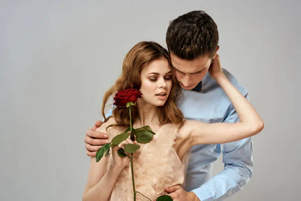 Fiatal pár ölelés romantika társkereső életmód kapcsolat fény háttér piros rózsa — Stock Fotó