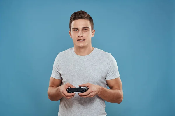 Un hombre con un joystick en sus manos entretenimiento tecnología de ocio videojuegos fondo azul camiseta blanca —  Fotos de Stock