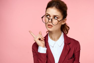 Kırmızı ceketli zarif bir kadın. Gözlüklü. Ofis müdürü, pembe arka plan.