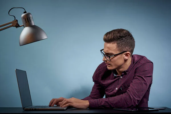 Um homem em uma camisa com um laptop na mesa é um gerente no escritório e um modelo de armário de lâmpadas — Fotografia de Stock