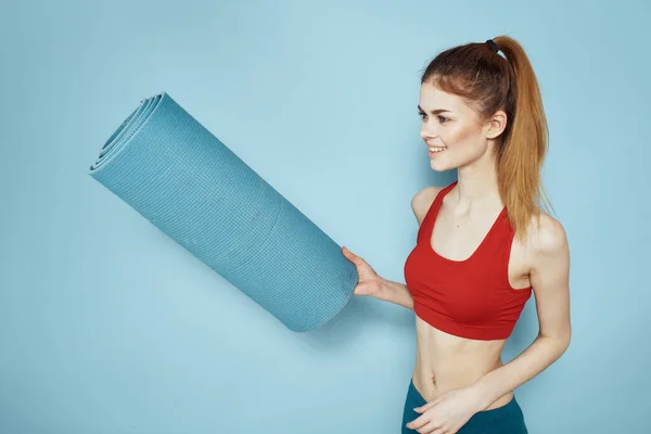 Esterilla de entrenamiento de mujer deportiva en las manos Red Tank Top ejercicio fondo azul — Foto de Stock