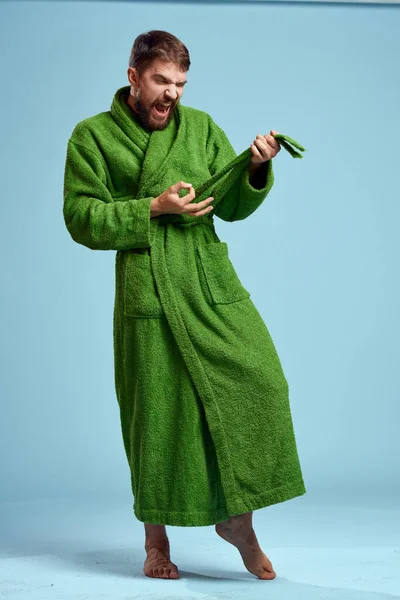 Человек в зеленом халате в полном рост на синем фоне босиком — стоковое фото