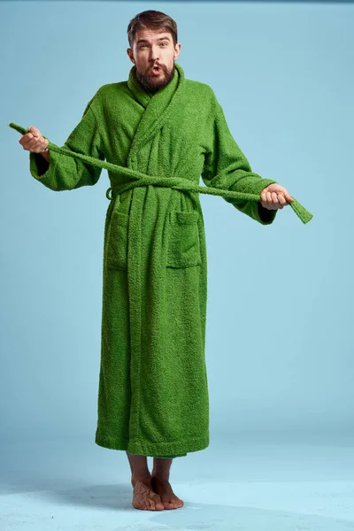 Un hombre con una túnica verde en pleno crecimiento sobre un fondo azul descalzo — Foto de Stock