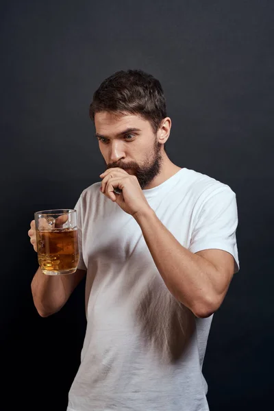 Man med en mugg öl i händerna känslor kul livsstil vit t-shirt mörk isolerad bakgrund — Stockfoto