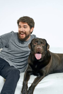 Beyaz bir kanepede siyah köpeği olan bir adam. Arka planda, yakın planda kesilen evcil hayvan insan arkadaş duyguları. Eğlenceli.