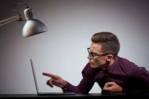 Бизнесмен в очках и рубашке сидит за столом с открытыми ноутбуками — стоковое фото