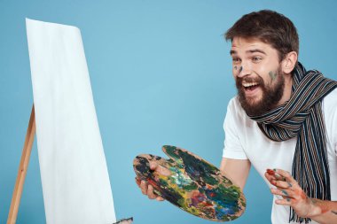 Erkek sanatçı palet fırçası resim sehpası mavi arka plan