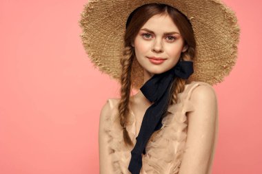 Şapkalı ve siyah kurdeleli güzel bir kadın. Pembe arka plan modeli.