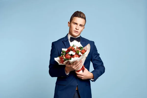 Romantische man met een boeket bloemen en in een strikje op een blauwe achtergrond bijgesneden uitzicht — Stockfoto