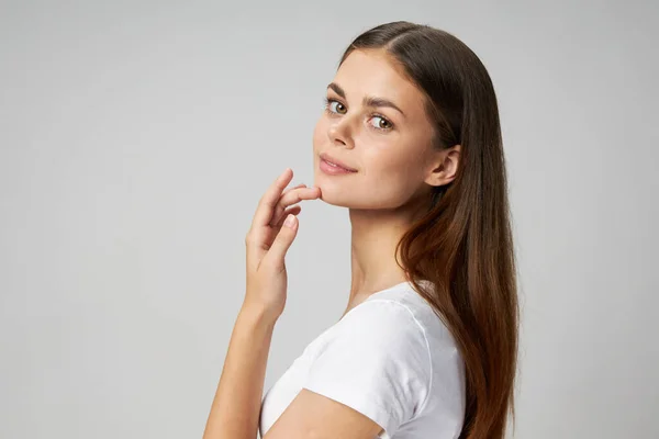 Una donna con una maglietta bianca si tocca il viso con la vista laterale della mano — Foto Stock