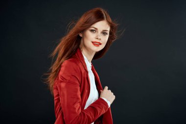 Uzun saçlı, kırmızı ceketli, makyajlı, dudakları koyu renkli bir kadın.