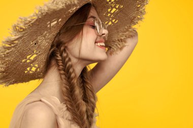 Saçları örgülü ve sarı arka planda şapkası olan güzel bir kadının portresi.