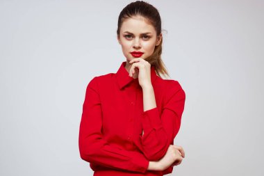Kırmızı dudaklı güzel bir kız ve arka planda açık renk jestleri olan bir gömlek.