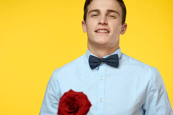 Gentleman in shirt and bow tie around his neck yellow background red rose — Stock Photo, Image