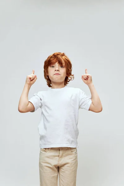 Portret van een roodharige jongen gebarentaal met zijn handen naar boven wijzend wit t-shirt Copy Space — Stockfoto