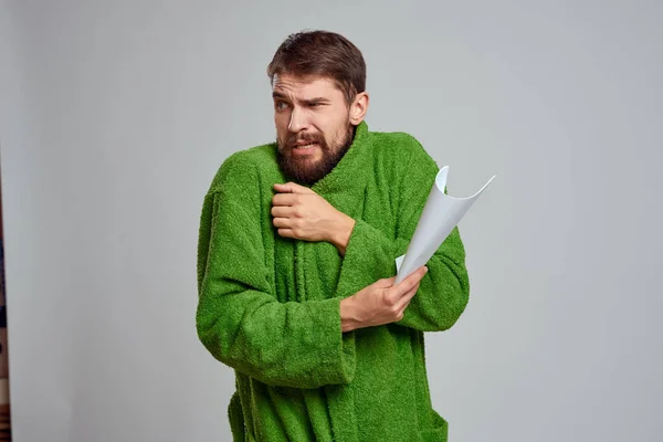 Emotionaler Mann in grünem Kleid mit einem zusammengerollten Blatt Papier auf hellem Hintergrund — Stockfoto