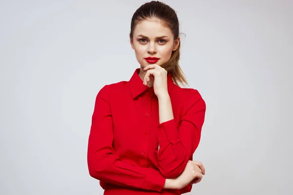 A beautiful girl with red lips and a shirt on a light background gestures with her hands — Stock Photo, Image