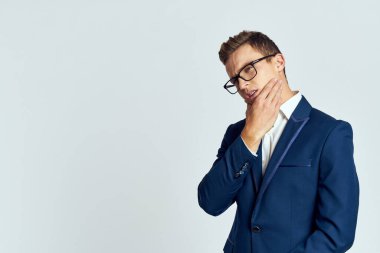 Gözlüklü bir iş adamı mavi takım elbiseli resmi ışık arkaplanı kesmiş.