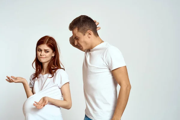 Een zwangere vrouw en een jonge man wachten op een baby op een lichte achtergrond emoties familie liefde — Stockfoto