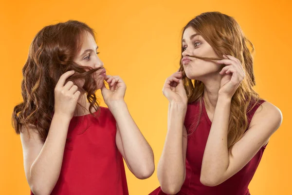 Gelukkig vrouw en klein meisje in rood jurk zijn het hebben van plezier op een gele achtergrond mode emoties zussen leuk kopiëren ruimte. — Stockfoto