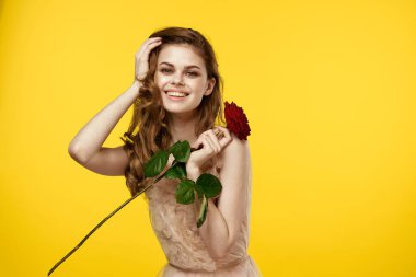 Sarı arka planda kırmızı gül ve gece elbisesi içinde romantik bir kadın.