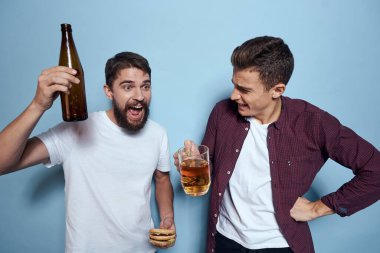 İki neşeli sarhoş arkadaş mavi bir arka planda bira içiyorlar.