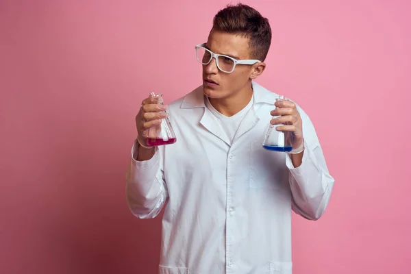 Assistant de laboratoire masculin avec des flacons dans les mains d'une substance chimique liquide multicolore — Photo