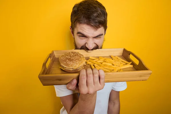 Hombre con paleta de madera comida rápida hamburguesa papas fritas dieta ingesta de alimentos de cerca — Foto de Stock